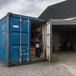 Brugt blå 20 fods container til opbevaring i indkørslen ved et dansk parcelhus